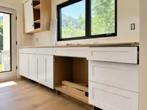 New painted-white shaker cabinet door fronts being mounted onto existing kitchen cabinet boxes, cabinet refacing in progress | Holz Industries, Kelowna